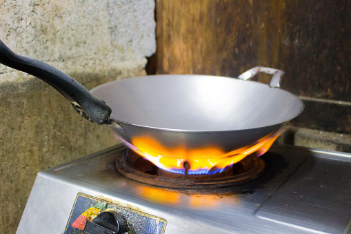 The pan is heating up on the gas stove, Preparing to fry or stir-fry.