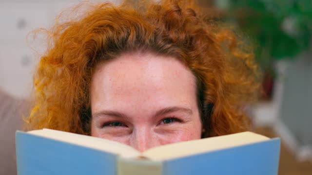 Female student hiding behind book, education in university