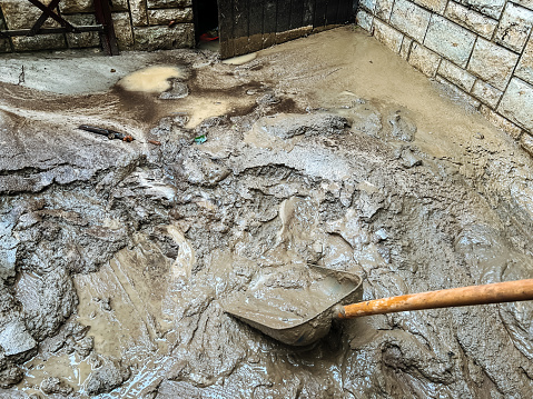 Removing river silt residue in yard after flooding of Kamniska Bistrica river at Nozice village with shovel.