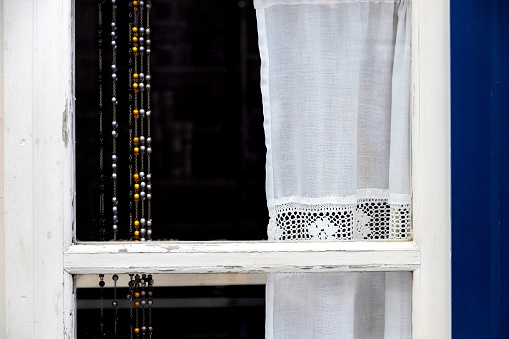 Window with traditional hand knitted curtains on a white wall, Spetses Island, Greece