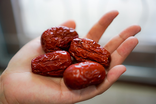 A close-up picture shows dried Chinese jujubes on the hand.