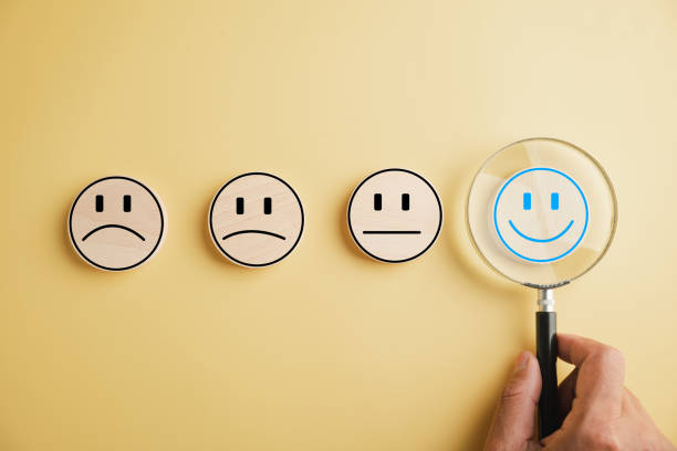 istock Magnifier in hand focuses on selected happy smiley face icon 1598040615