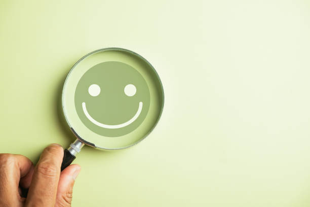 istock Magnifier in hand focuses on selected happy smiley face icon 1598041148