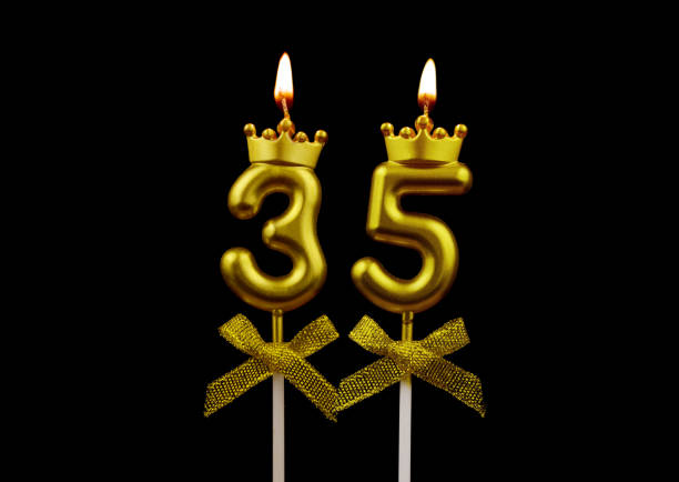 Gold birthday candles burning on white, number 35. stock photo