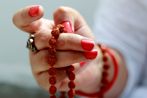 Unrecognizable person holding rudrakasha in hands worshiping in front of temple.