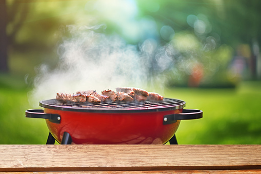 summer time party in backyard garden with grill BBQ, wooden table, blurred background