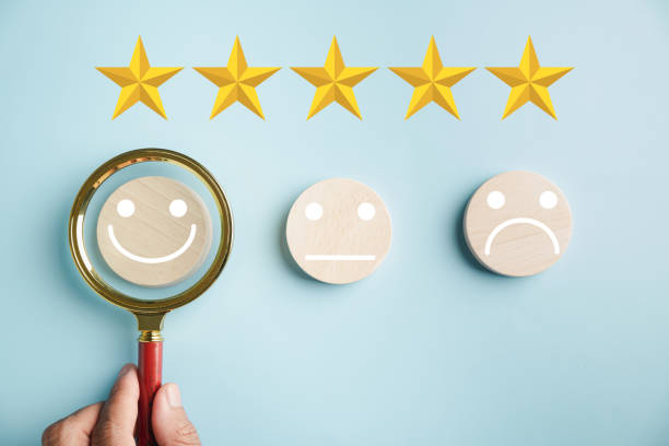 istock Magnifier in hand focuses on selected happy smiley face icon 1598043996
