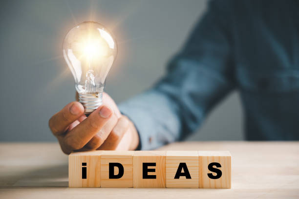 istock Hand holding light bulb with wooden block displaying word Ideas 1598044572