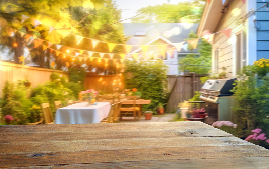 Empty wooden table with party in backyard at night, blurred  background