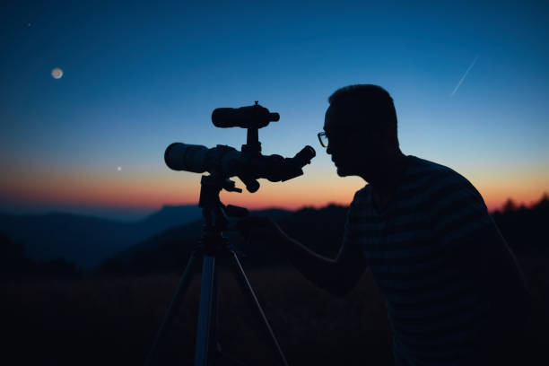 istock Astronomer looking at the starry skies and crescent Moon with a telescope. 1598059236