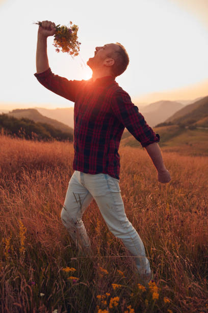 Man holding field flowers in nature.