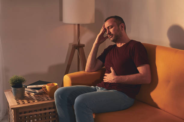 istock Man with stomach and head pain at home. 1598070596