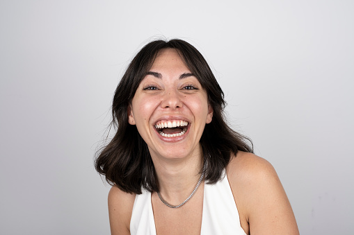 Portrait of cheerful woman looking at camera with happiness facial expression over gray background. Horizontal. Studio shot.