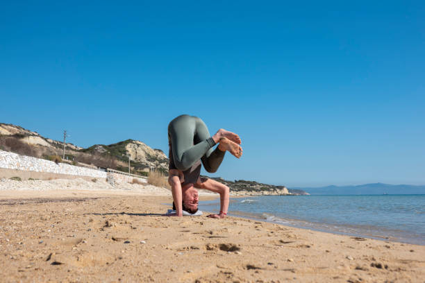 istock Attractive middle-aged woman practicing yoga on a beautiful beach 1598127289