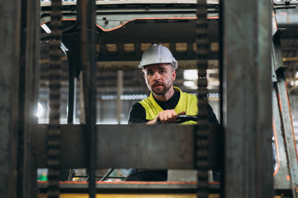 istock Industrious Engineer Operating Forklift in Warehouse. Efficient Forklift Driving in Factory. Engineer is working and maintaining in the factory. 1598130473