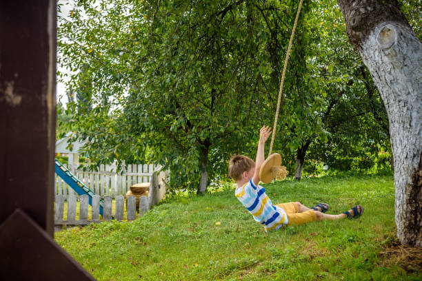 istock Happy little boy is having fun on a rope swing which he has found while having rest outside city. Active leisure time with children 1598150009