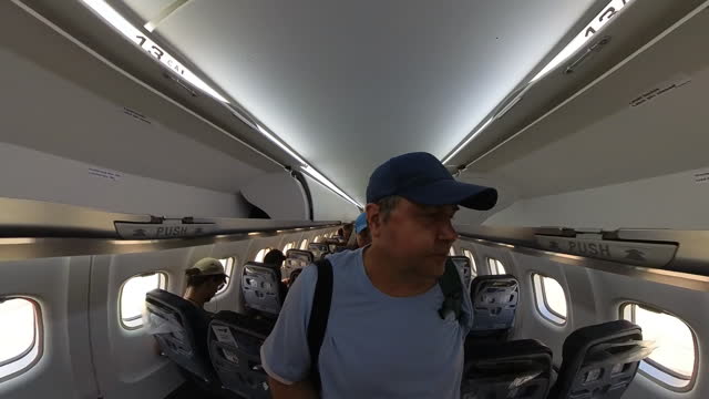 Passenger man walking inside plane and searching his place.