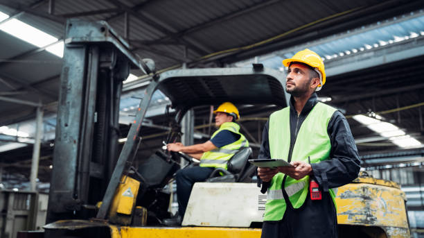 istock Industrious Engineer Operating Forklift in Warehouse. Efficient Forklift Driving in Factory. Engineer is working and maintaining in the factory. 1598155681