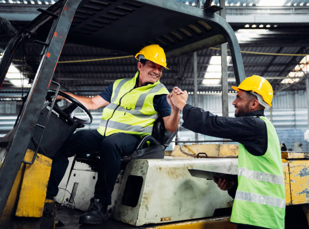 istock Industrious Engineer Operating Forklift in Warehouse. Efficient Forklift Driving in Factory. Engineer is working and maintaining in the factory. 1598156221