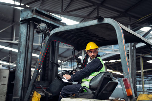 istock Industrious Engineer Operating Forklift in Warehouse. Efficient Forklift Driving in Factory. Engineer is working and maintaining in the factory. 1598157279