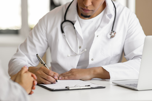 Doctor talking in clinic room and handing a prescription to the patient