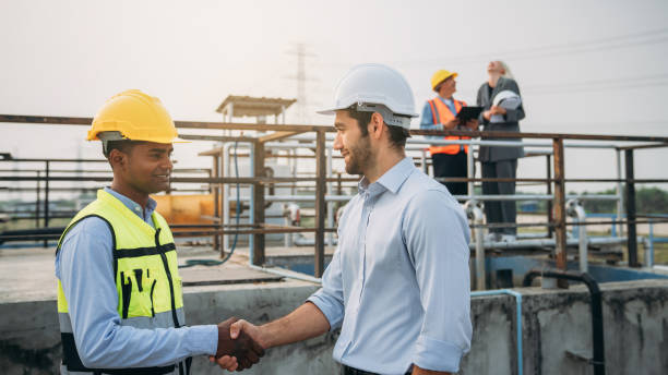 istock Success Stacked and Shake in a Hand. Professional Technician Ensuring Pollution Control in Wastewater Treatment Plant. Worker checking the waste water treatment pond industry. 1598163619