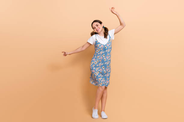 full body size photo of carefree girl dance have fun wear flowers print dress listen music music rhythm isolated on beige color background - tail light imagens e fotografias de stock