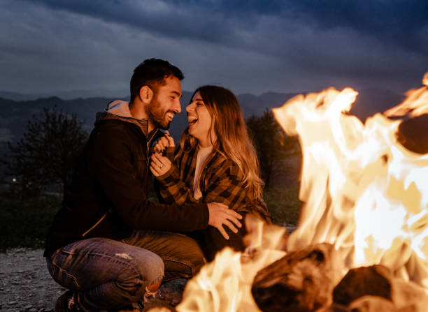 istock lovely passionate couple in front at the fire camping 1598185318