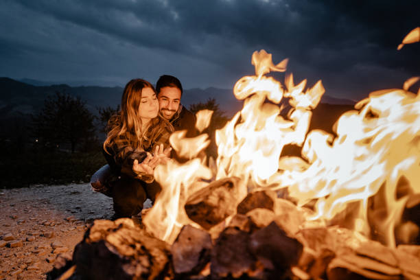istock lovely passionate couple in front at the fire camping 1598186640