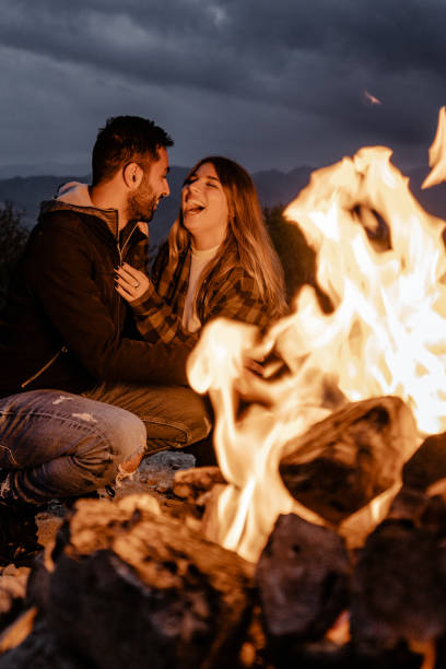 istock lovely passionate couple in front at the fire camping 1598187167