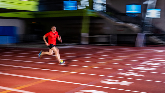 Sporty young man running on the athletic track background