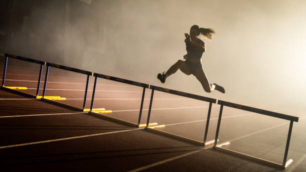 athlète sautant par-dessus l’obstacle - hurdle competition hurdling vitality photos et images de collection