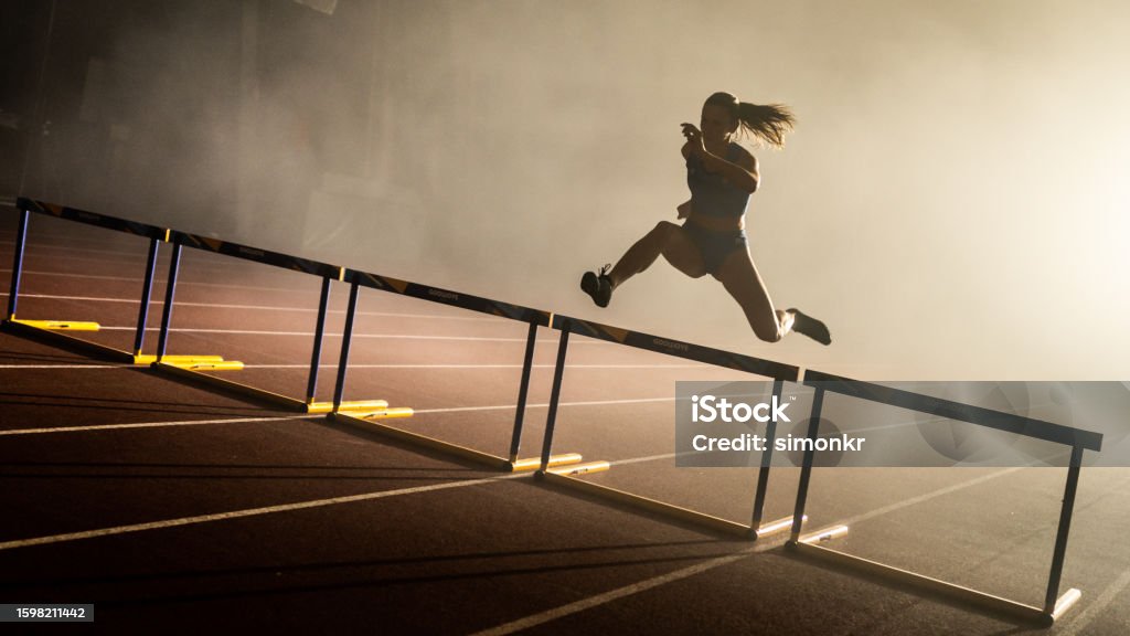 Athlete jumping over hurdle Athlete young woman jumping over hurdles during practice. Sports Race Stock Photo