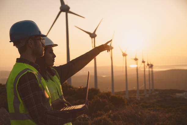 istock Young maintenance engineer team working in wind turbine farm at sunset 1598229740