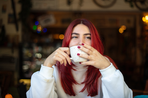 Pretty young woman is drinking coffee at coffee shop.