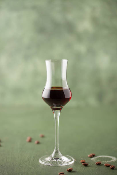 кофейный ликер в стильном бокале для граппы и кофейные зерна на столе - coffee alcohol wine chocolate стоковые фото и изображения