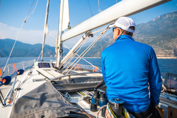 Young man captain on the yacht looking through binoculars during sailing boat control. Travel and active life. High quality photo