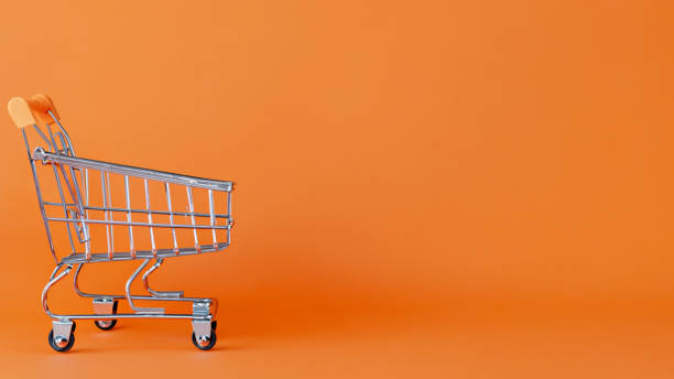 einkaufswagen auf orangefarbenem hintergrund - shopping bag orange bag handle stock-fotos und bilder