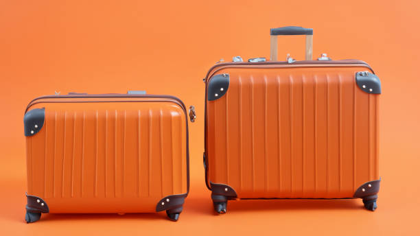 istock Orange holiday suitcase on wheels with shadow on orange background 1598260511