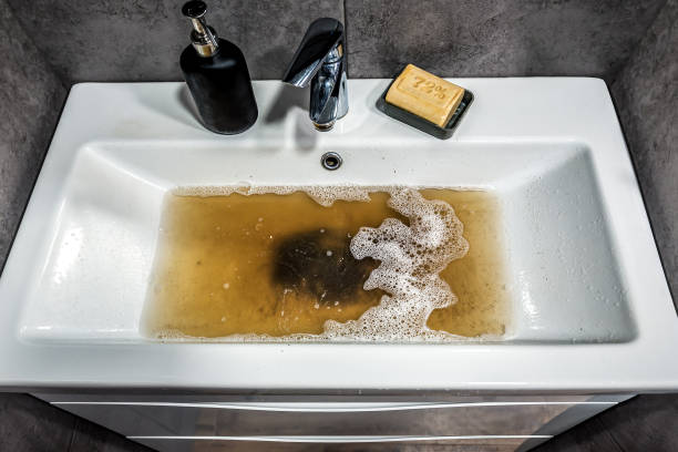 istock Clogged white sink in bathroom, sink with dirty water, brown soap. Plumbing problems. 1598270384