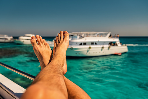 Human legs on the boat in the sea. Vacation theme