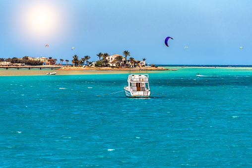 View of a yacht and a beautiful island and many kite surfers on the Red Sea in Egypt. Summer vacation theme