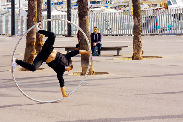 Young street artist , juggler playing upside down with large ring, Barcelona, Catalonia, Spain.