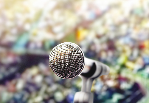 Dynamic microphone in front of an enormous crowd at a music, public speaking or political event.