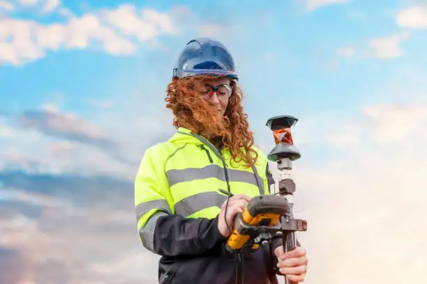 Photo of Female Woman land surveyor working with moder surveying geodesic instrument tachometer checking coordinates of land for development. Young pretty woman working in construction industry