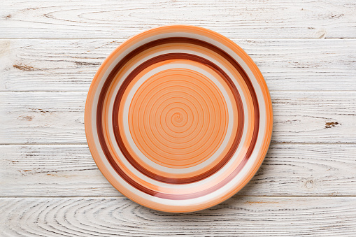 Top view of empty orange plate on wooden background. Empty space for your design.