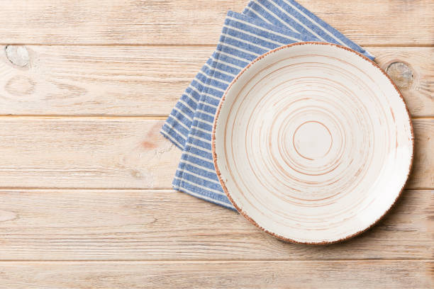 istock Top view on colored background empty round white plate on tablecloth for food. Empty dish on napkin with space for your design 1598308401