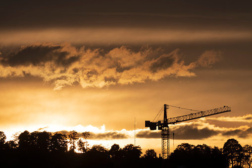 The silhouette of a construction crane in the evening light