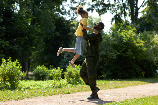 African American military dad playing with his child during their walk outdoors