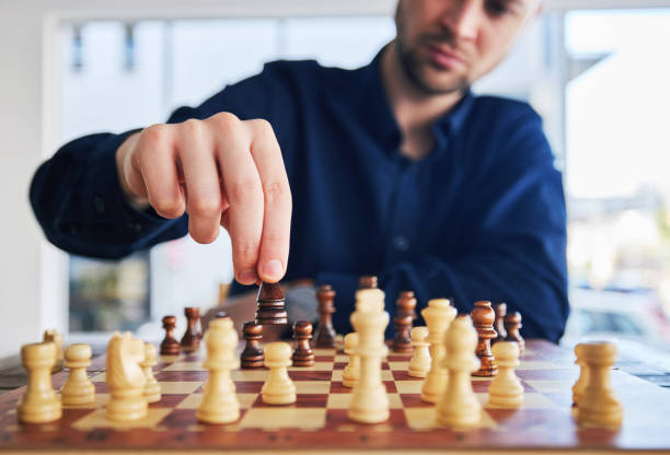 istock Chess, man moving a piece and game of strategy, problem solving or person playing on chessboard in competition. Planning, choice and hand on knight or king, queen and player thinking of winning move 1598386815